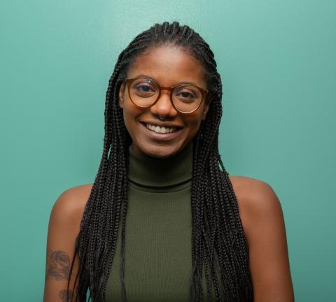 This is a picture of a woman with a green shirt and a teal background.